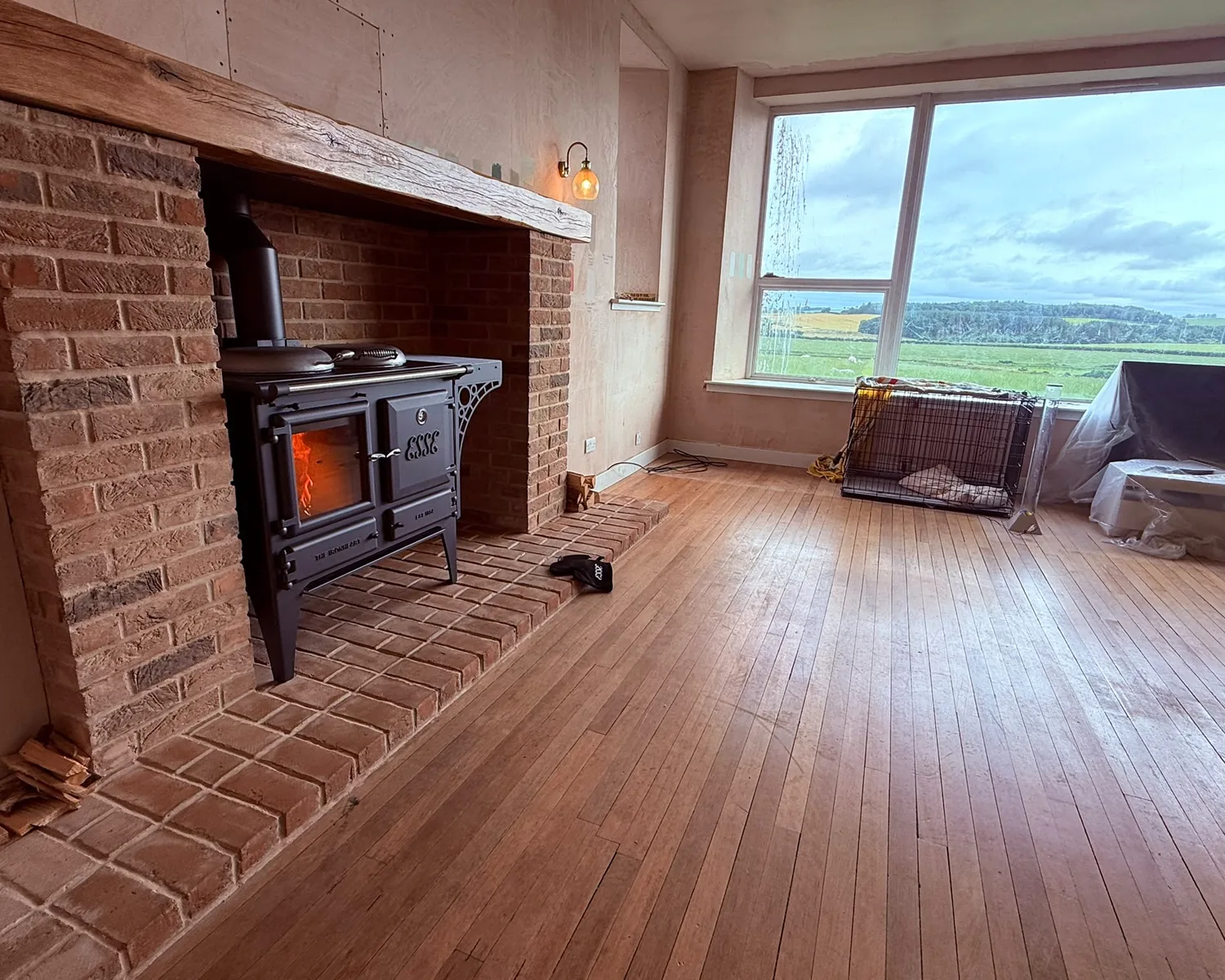 Range-style stove fitted in a rebuilt brick fireplace with an oak beam
