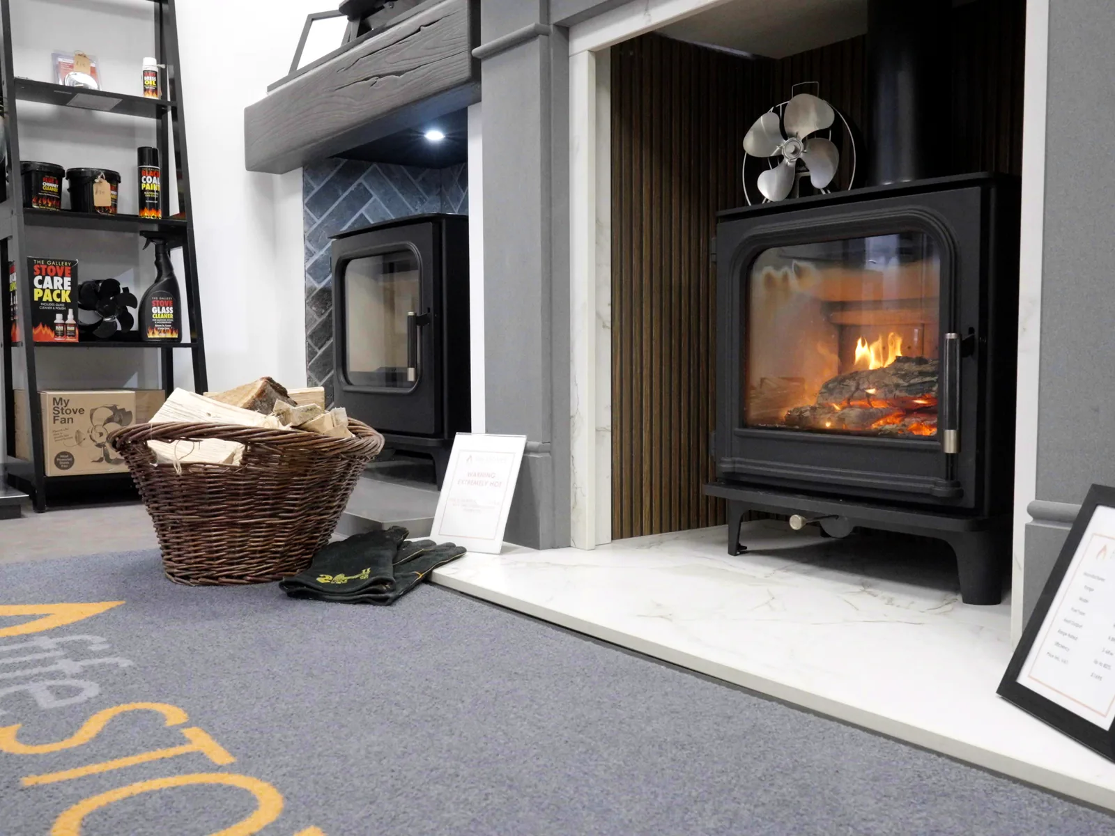 A lit stove on display with a log basket in the Fife Stoves showroom, Kirkcaldy